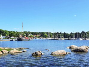 A marina with boats docked, a clear sky, and a forested hill in the background. - 5 Star Holiday Home in Navekvarn (Navekvarn)