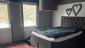 Makuuhuone, jossa on sänky, ikkuna, patteri ja seinään kiinnitetty valaisin.