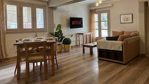 A living room with a wooden dining table, a sofa, a TV, and a potted plant. - Casa de Lama ~ Expat friendly, 2 Bedrooms, A/C (Degla Maadi)