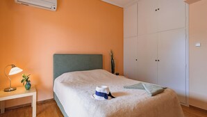 Een slaapkamer met een bed, nachtkastje, lamp en een kledingkast.