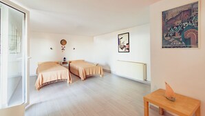 Een kamer met twee bedden, een radiator, een tafel met een decoratief object en een muur met een lijst eromheen.
