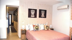 A bedroom with a pink bedspread, two wall-mounted air conditioning units, and two framed artworks above the bed. - Nel Cuore del Capo  (Palermo)