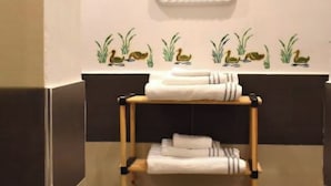 A bathroom with a towel rack holding folded towels, a wall with duck illustrations, and a tiled floor. - Nel Cuore del Capo  (Palermo)