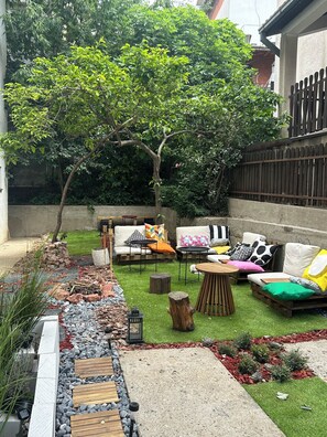 Eine Terrasse mit Gartenmöbeln, einem kleinen Tisch und einem Baum.