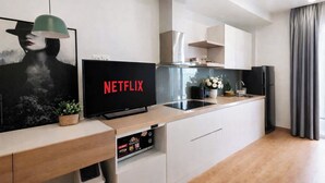 A modern kitchen with a built-in oven, a coffee machine, and a flat-screen TV displaying 'NETFLIX'. - Vinhomes D'capital Pearl of Hanoi (Hanoi)