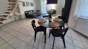 Un salon moderne avec un coin repas, un escalier et une grande fenêtre.
