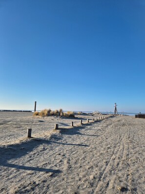 Ein Sandstrand mit einer Holzpromenade, die zu einem Rettungsturm führt.