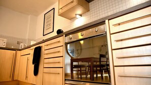A kitchen with wooden cabinets, a built-in oven, and a dining table with chairs. - The Comfort Hub, Leeds Train Station (Leeds)