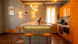 Une cuisine moderne avec un coin bar, des tabourets de bar, une bouteille de champagne et une machine à café.