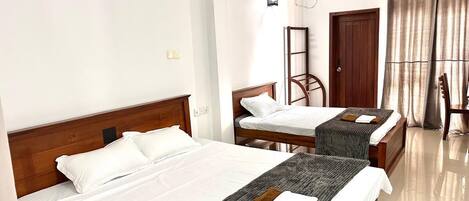 A hotel room with two beds, a wooden headboard, a small table, and a chair.