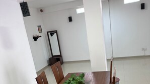 A conference room with a wooden table, chairs, a potted plant, and a large mirror on the wall. - Serrena Airport Guest House - Colombo (Seeduwa)