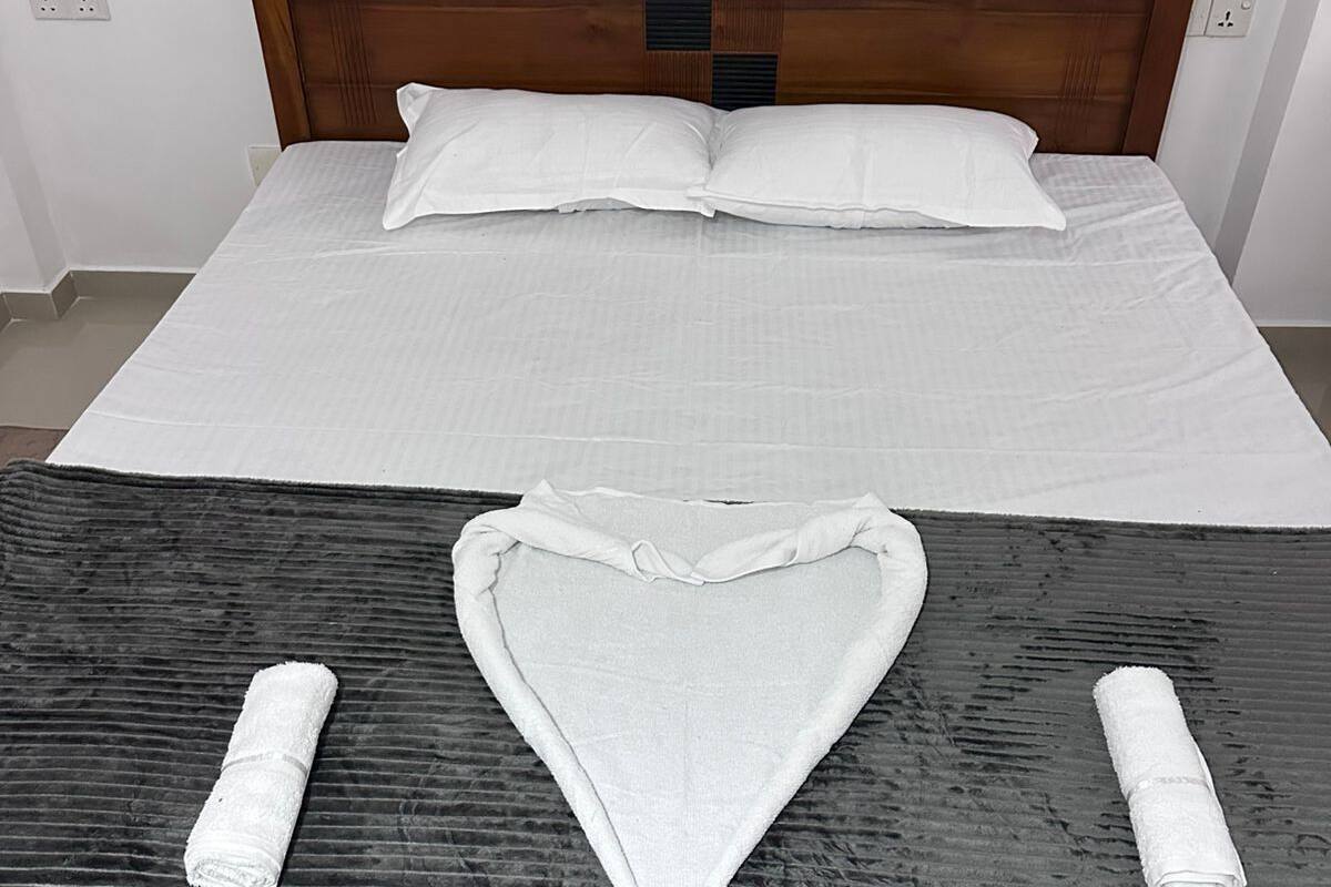 Ein Bett mit einem Holz-Kopfteil, weißer Bettwäsche und zwei Handtüchern, die darauf drapiert sind.