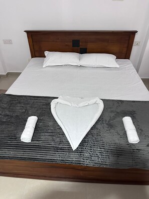 A bed with a wooden headboard, white bedding, and two towels arranged on the bed. - Serrena Airport Guest House - Colombo (Seeduwa)