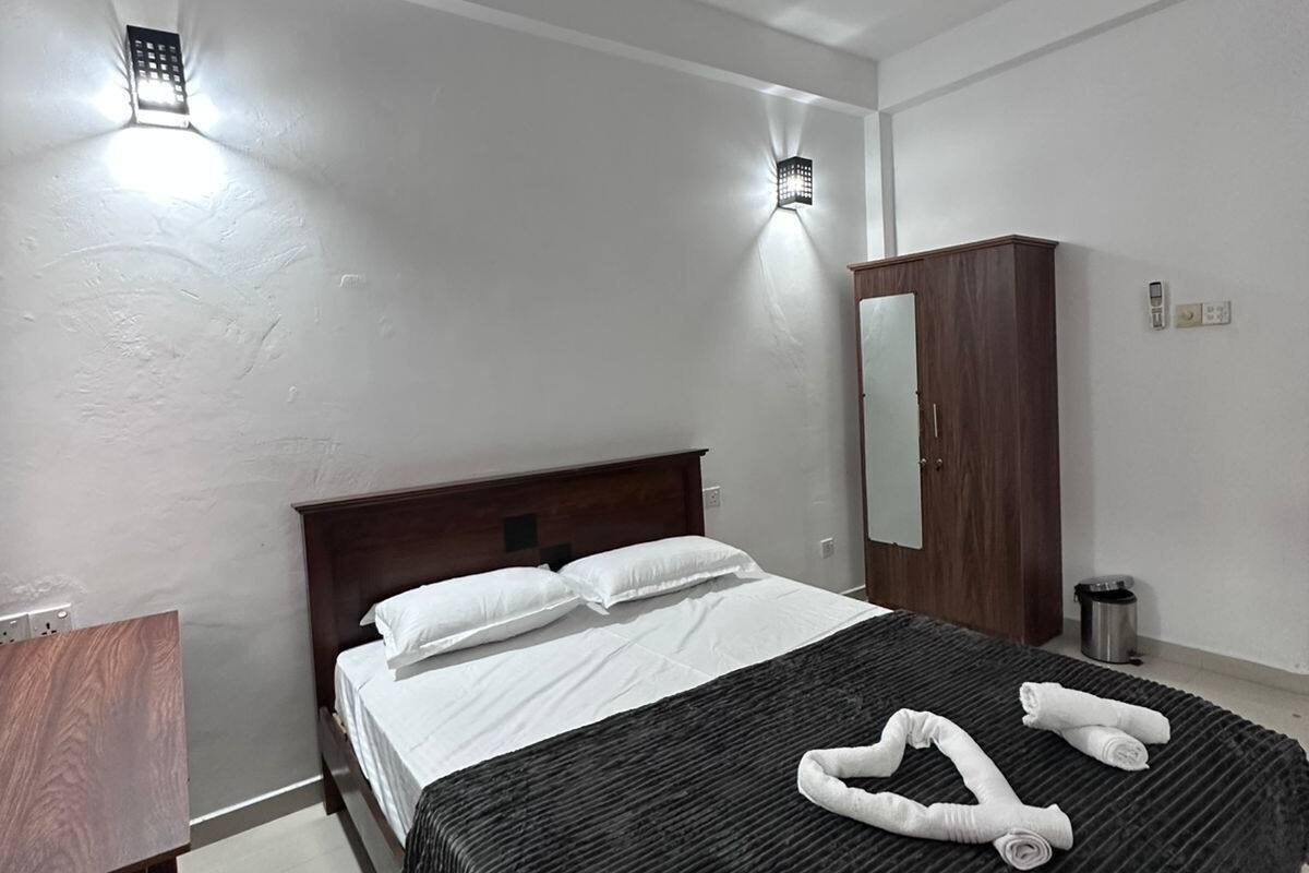 Ein Hotelzimmer mit Bett, Holzschrank, Spiegel und Deckenventilator.