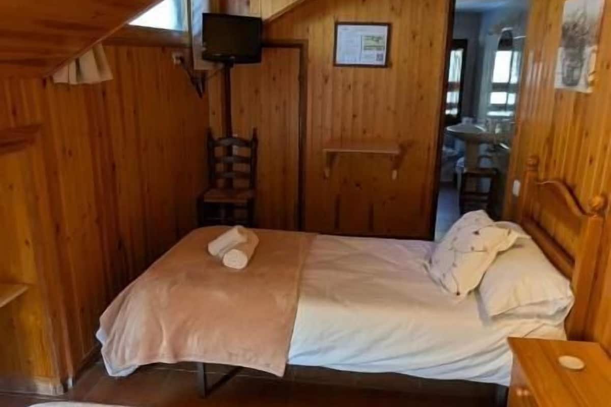 Une pièce de style cabane en bois, comprenant deux lits, une chaise, un bureau et un téléviseur.