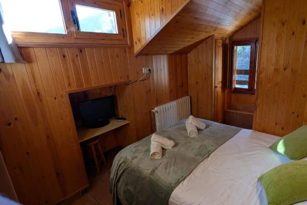 Une pièce en bois avec un lit, une télévision et une fenêtre.