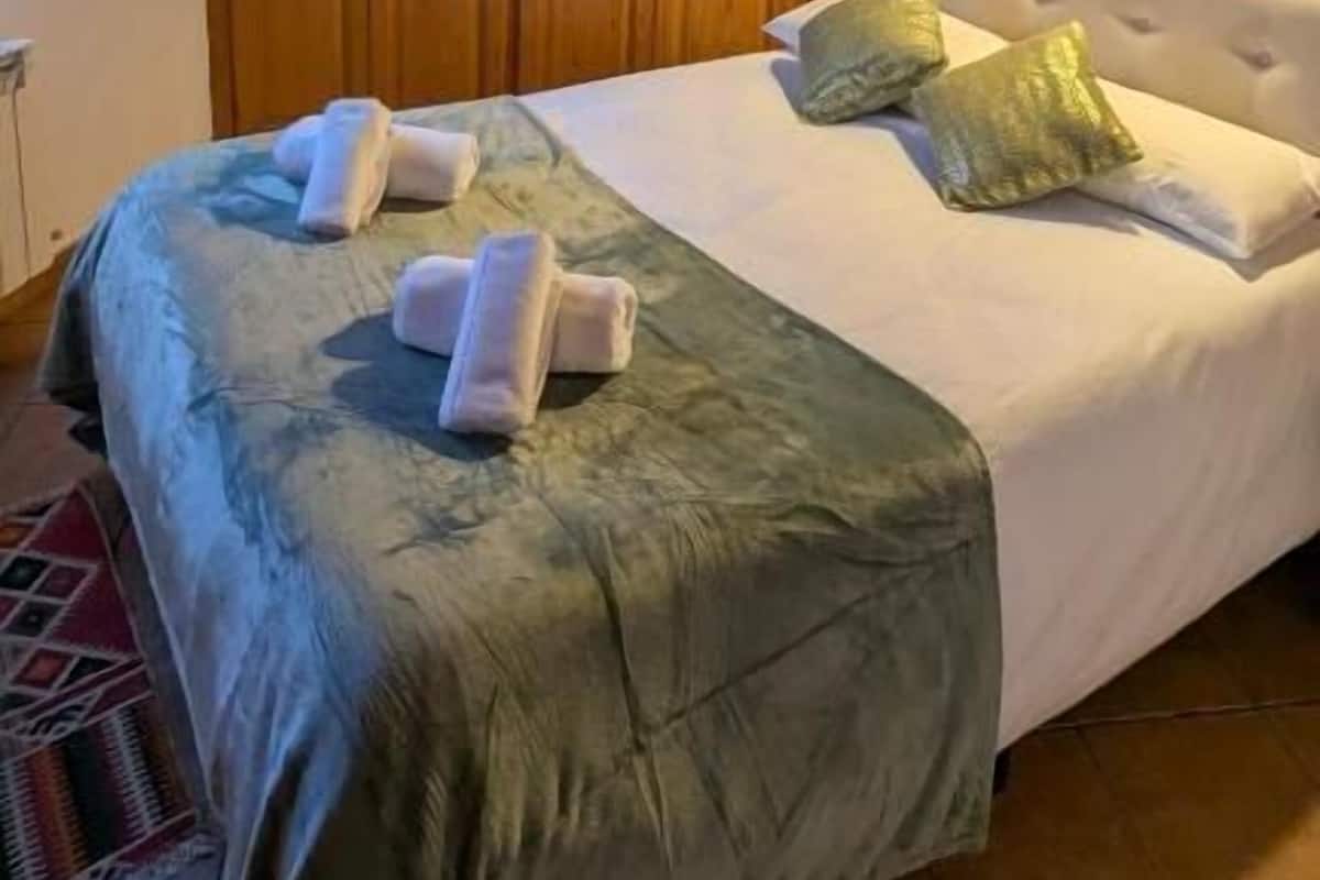 Une pièce aux murs lambrés, avec un lit, deux oreillers et une couverture.