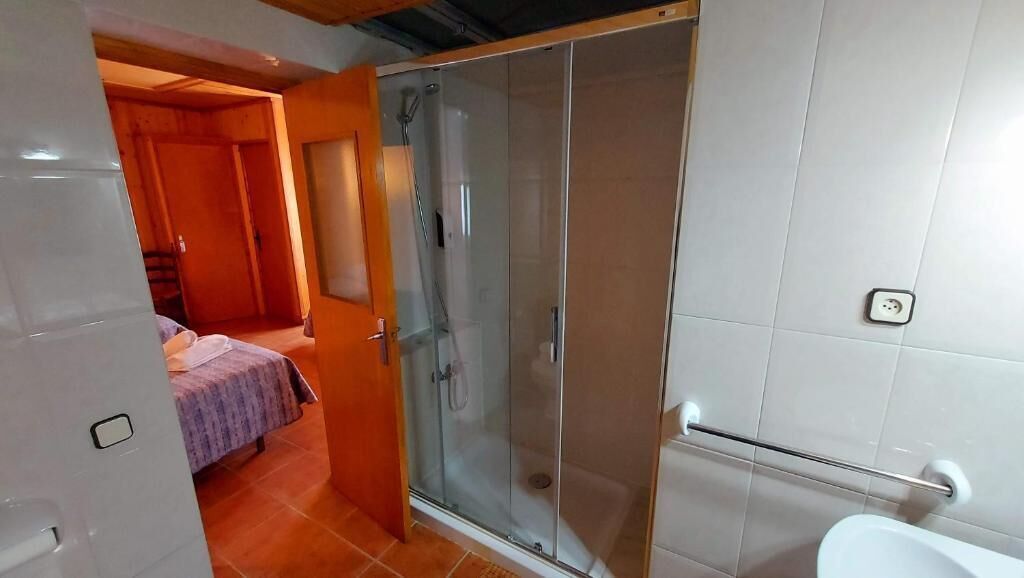 A bathroom with a glass shower enclosure, a toilet, and a sink.