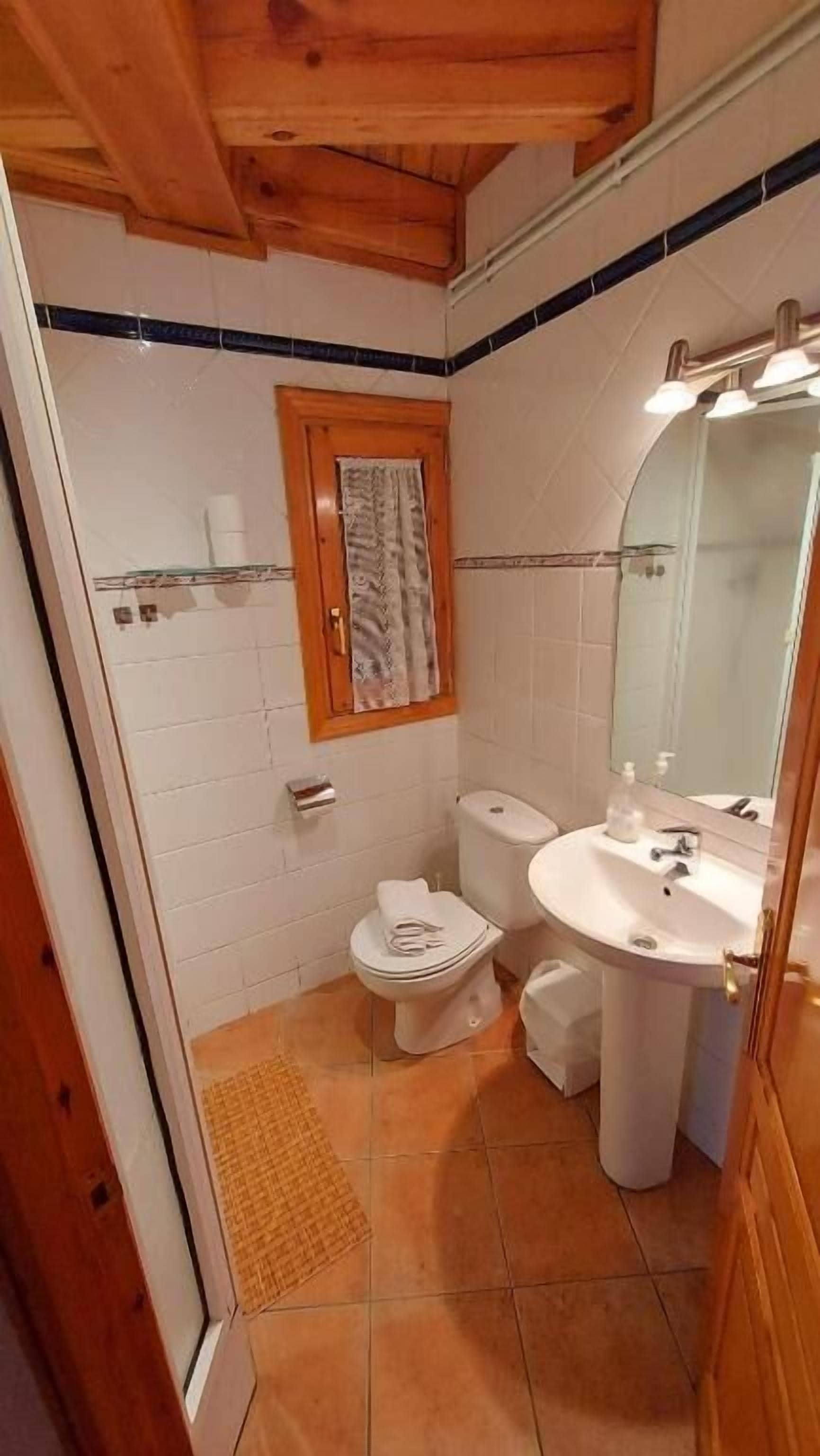 Un baño con inodoro, lavamanos y espejo.
