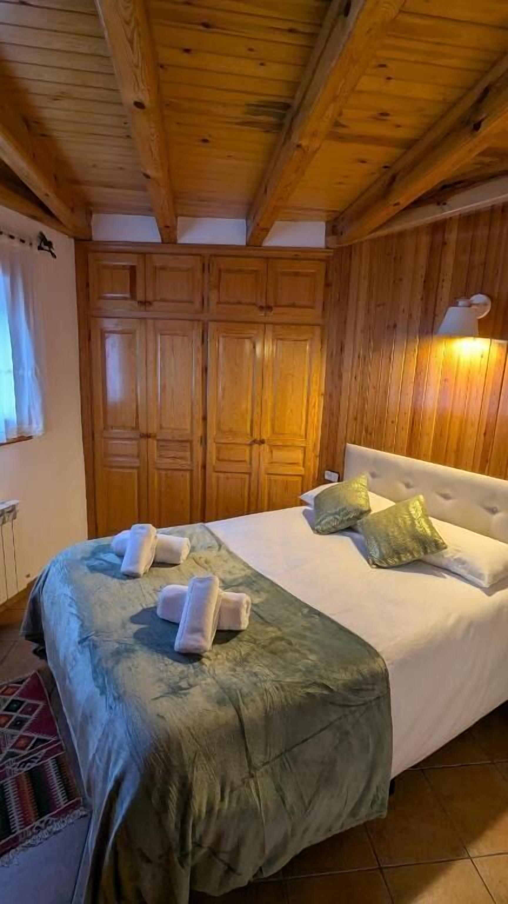 Habitació amb panells de fusta, un llit, almoadines i tovalloles.