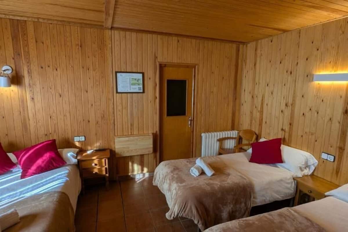 Une pièce en bois avec deux lits, une table de chevet, un radiateur et une porte.