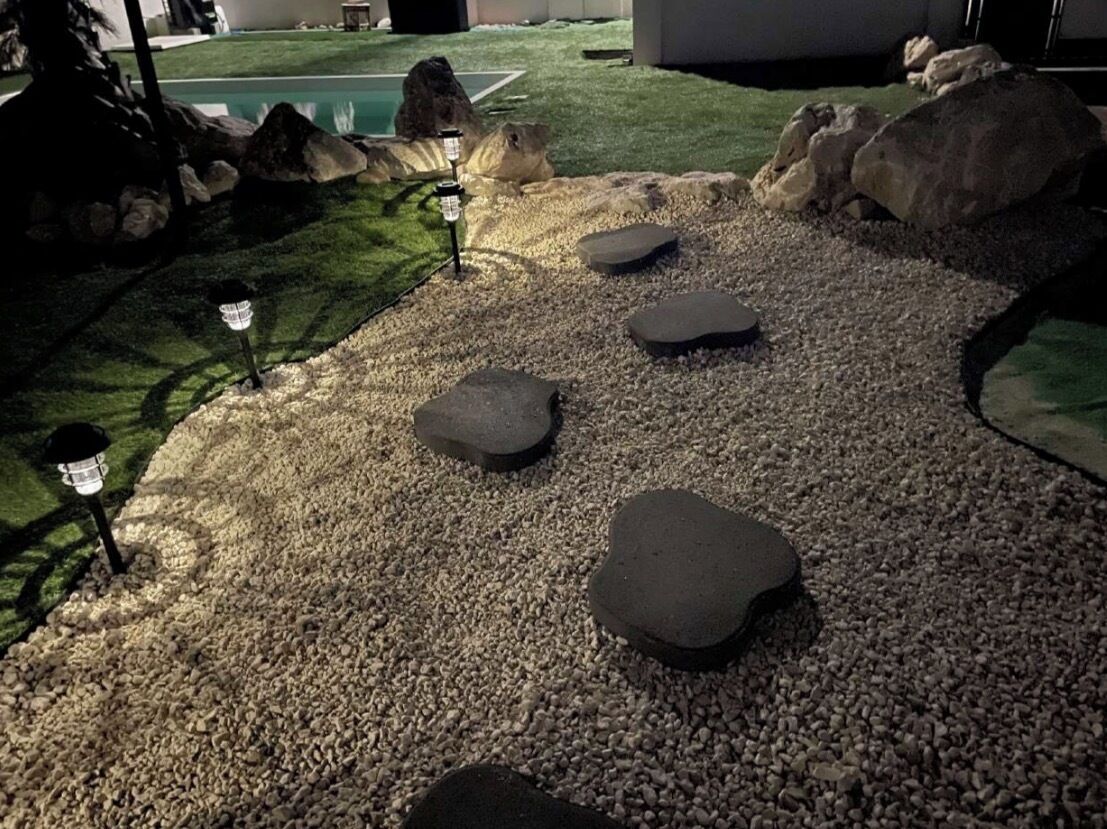 A landscaped area with pebbles, rocks, and a pool.