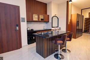 A modern kitchen with a marble countertop, wooden cabinets, and a built-in island with bar stools.