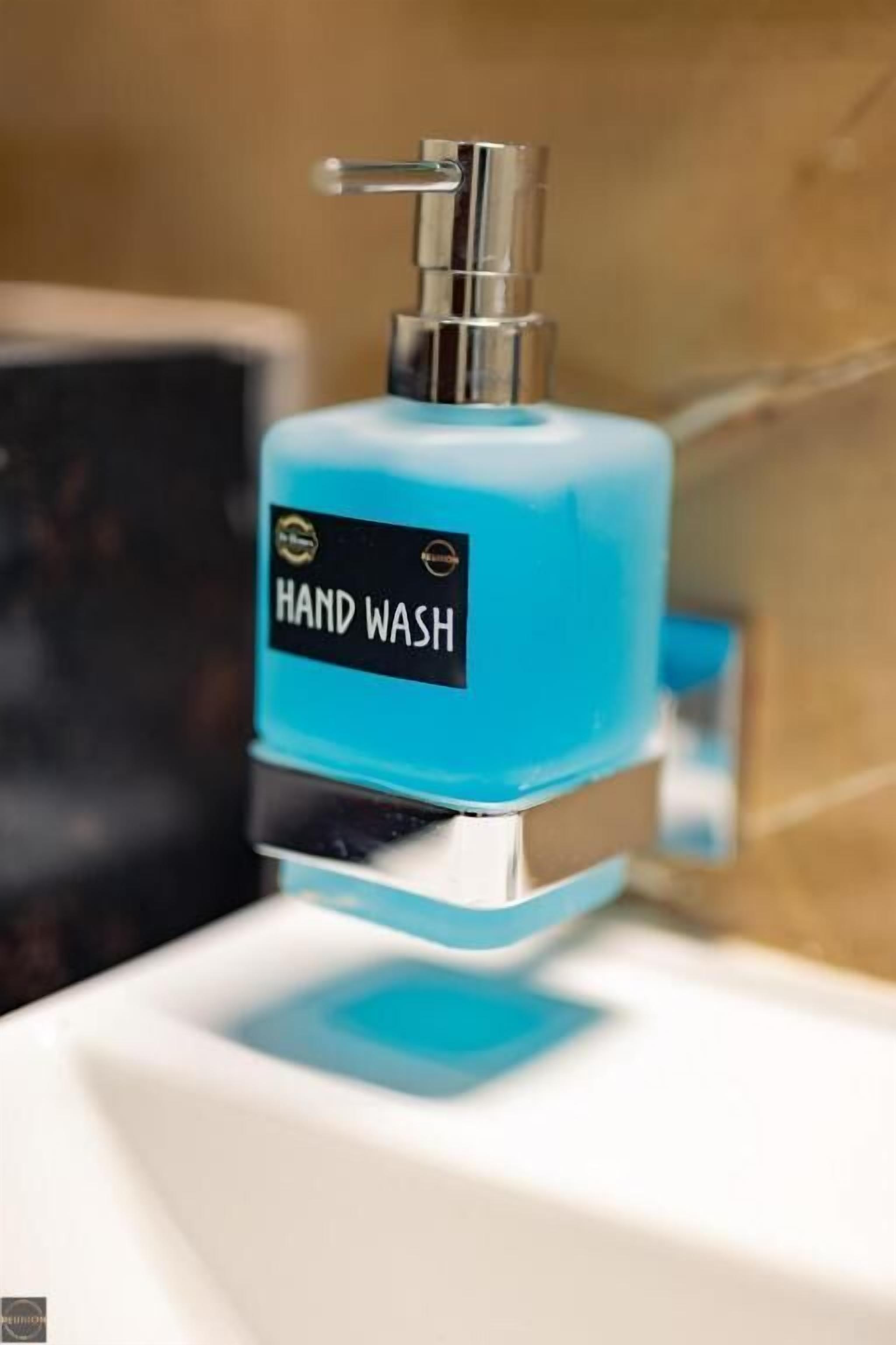 Un punto di erogazione sapone mani con pompa blu ed etichetta nera.