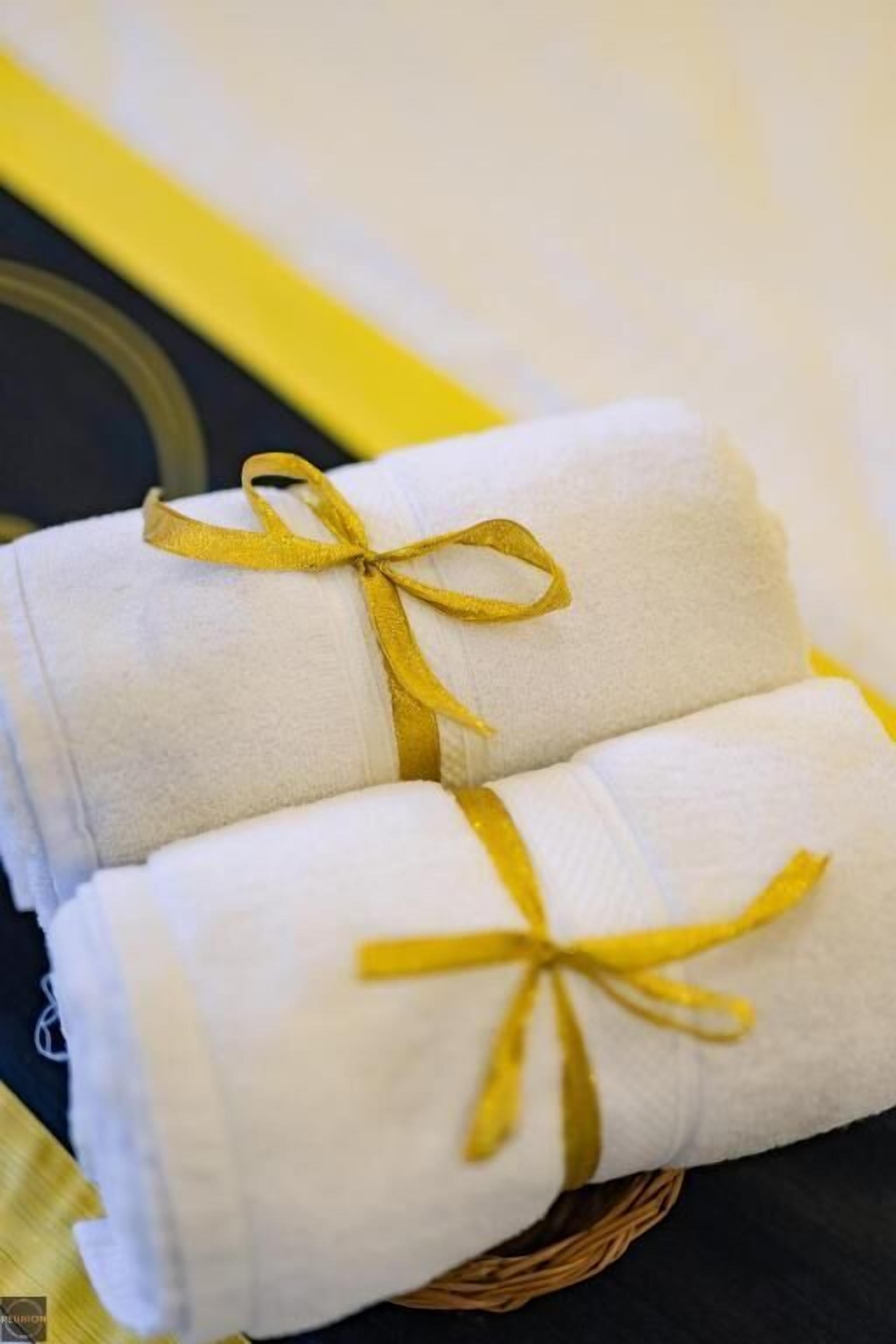 Due asciugamani piegati con cura legati con un nastro giallo, posti in un cesto di vimini.