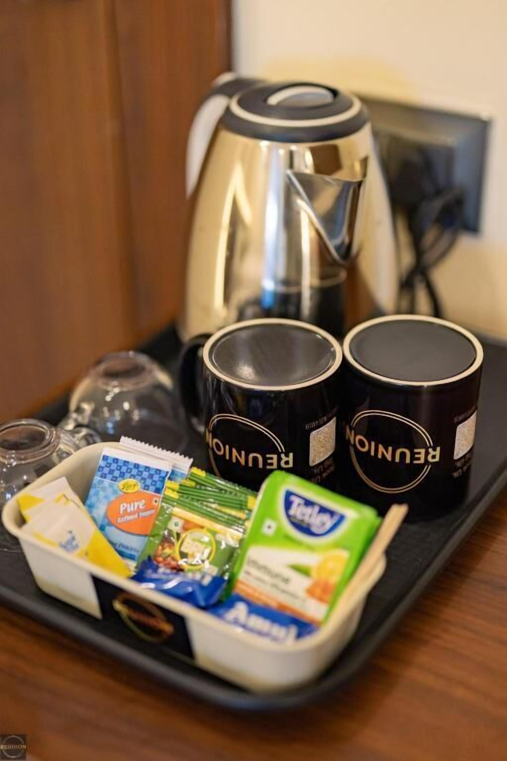 A tray with a coffee maker, two mugs, a box of tissues, and a pack of tissues.