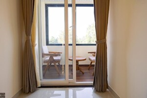 A room with a sliding glass door leading to an outdoor patio with two wooden tables and chairs.