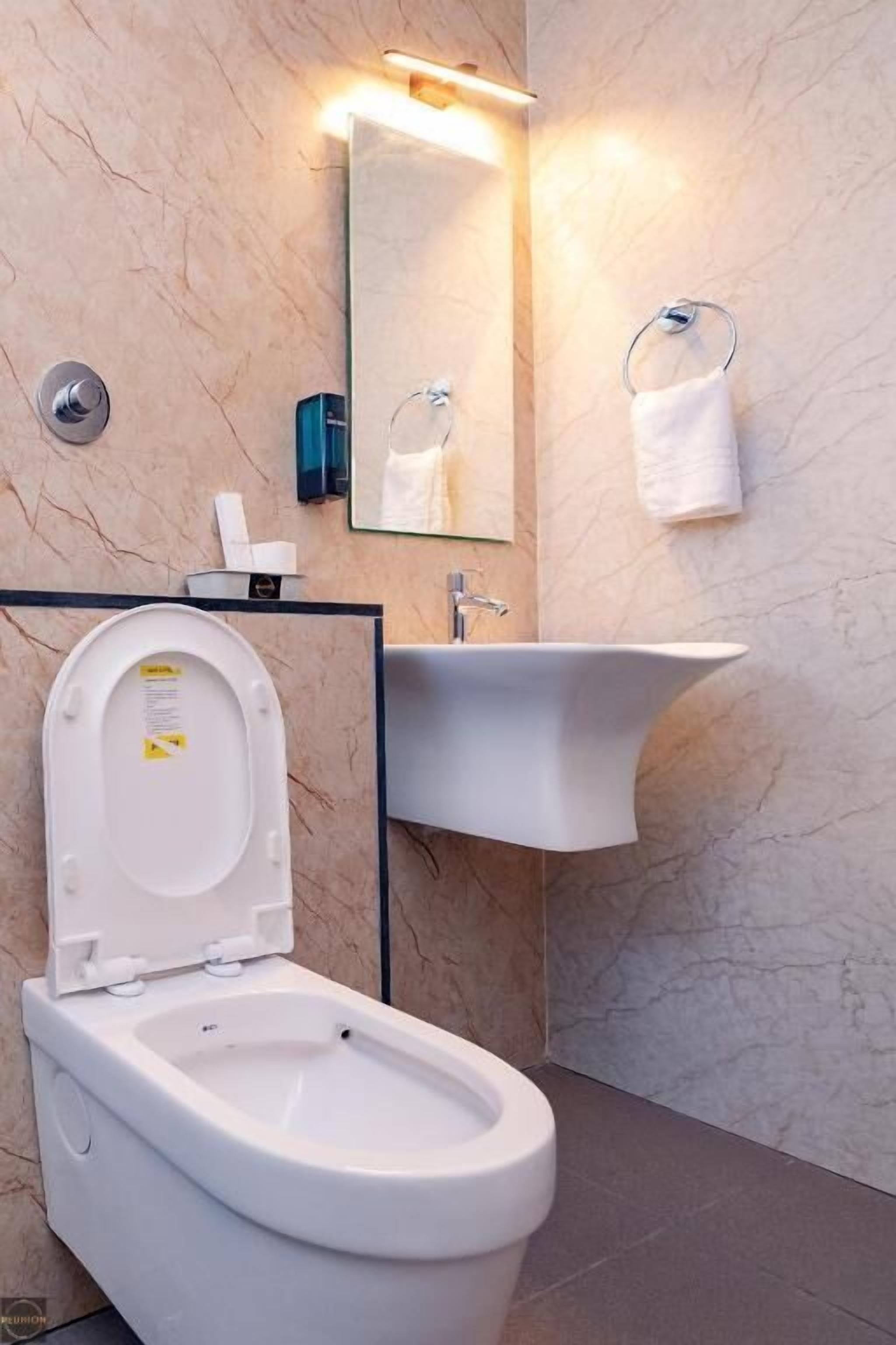 A modern bathroom with a toilet, sink, and mirror.