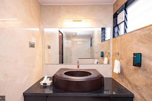 A modern bathroom with a large mirror, a round sink, and a towel rack.