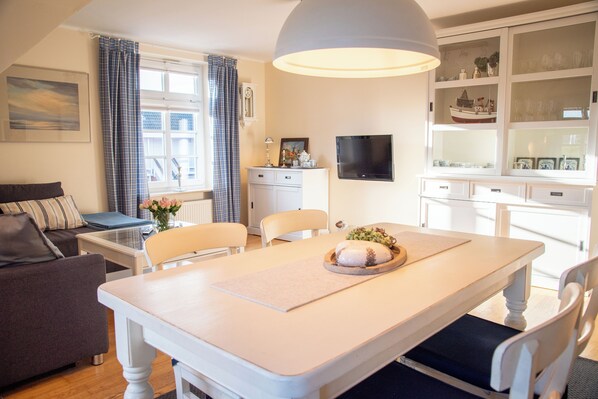 A dining area with a table, chairs, a television, and a cabinet with glass doors.