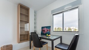Uma sala de jantar com mesa, cadeiras, um quadro e uma janela com vista.