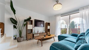 Uma sala de estar moderna com um sofá, uma mesa de centro, uma TV e uma escada.