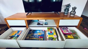 A television on a wooden stand with two drawers below containing board games. - Apartment Anouk Centrally located, cozy family apartment with sunny terrace (Lenk)
