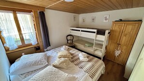A room with a bunk bed, a single bed, a wooden wardrobe, and a window with curtains. - Apartment Anouk Centrally located, cozy family apartment with sunny terrace (Lenk)