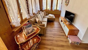 A cozy living room with a sofa, TV, and a small cart with magazines. - Apartment Anouk Centrally located, cozy family apartment with sunny terrace (Lenk)