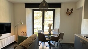 Un salon moderne comprenant un canapé, une table à manger, des chaises, un téléviseur et une tête de cerf décorative.