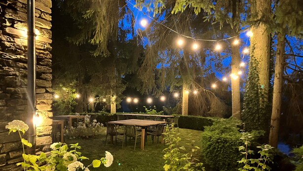 Un bâtiment en pierre doté d’un patio, de guirlandes lumineuses et de mobilier d’extérieur.