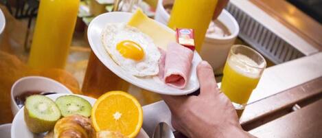 A breakfast setting with a plate of food, a glass of orange juice, and a bottle of juice.
