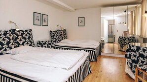 A room with two beds, a wooden floor, a dining table with a chair, and a mirror. - 4 Person Holiday Home in Brovst (Brovst)