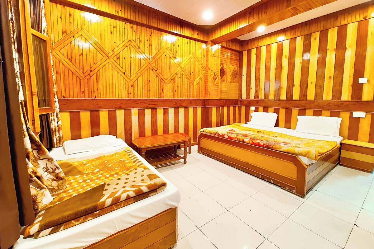 Ein Zimmer mit zwei Betten, einer Bank und einer Wand mit Muster.