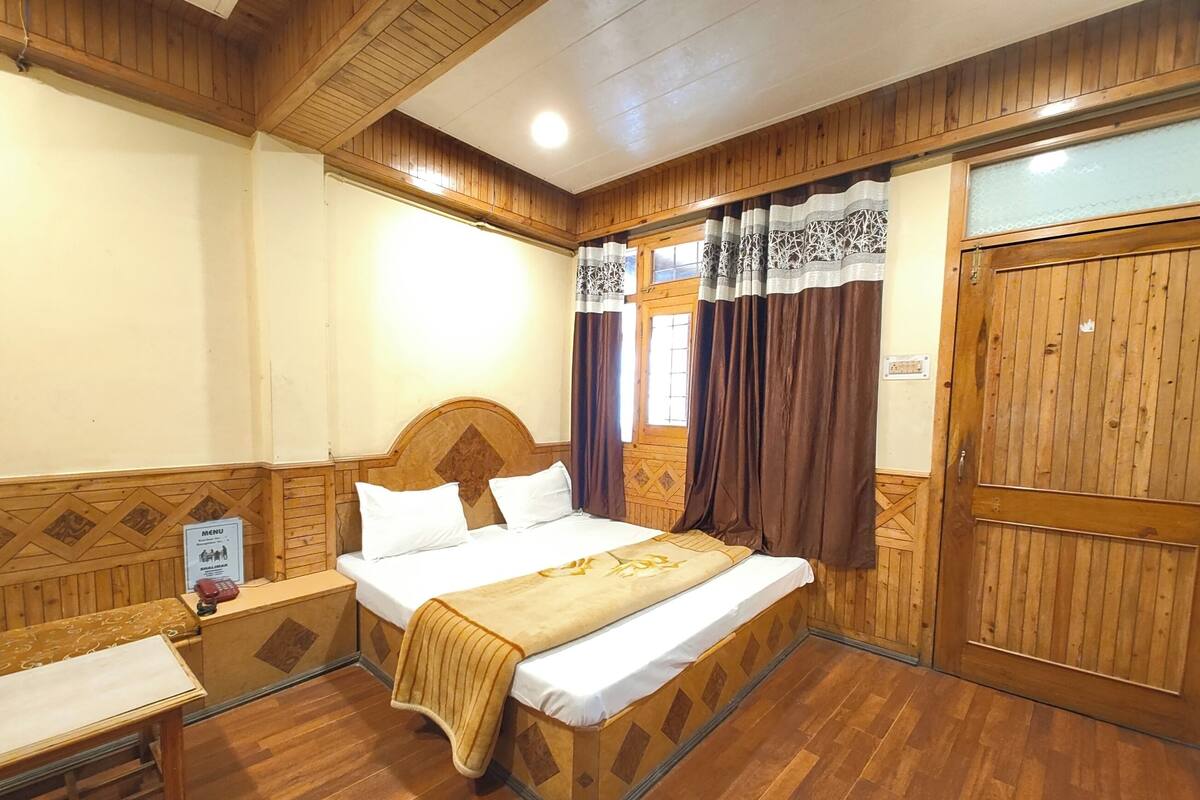 Ein Zimmer mit Holzwänden, einem Bett, einem Nachttisch, einem Beistelltisch und einem Kleiderschrank.