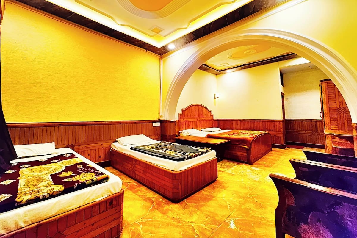 Ein Hotelzimmer mit Holz-Kopfteil, einem Bett mit gemustertem Überwurf, einer hölzernen Bank und einem Marmorboden.