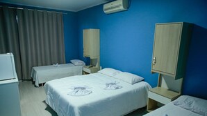 Habitación de hotel con dos camas, un escritorio, una silla, un armario y un equipo de aire acondicionado.