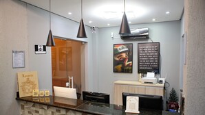 Zona de recepción de un hotel con mostrador, una impresora Samsung, un letrero que dice 'Locatelli' y un equipo de aire acondicionado de pared.