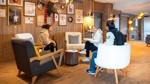A room with wooden walls, framed pictures, a mounted deer head, and modern furniture. - Retreat With Shared Pool and Terrace (Huez)
