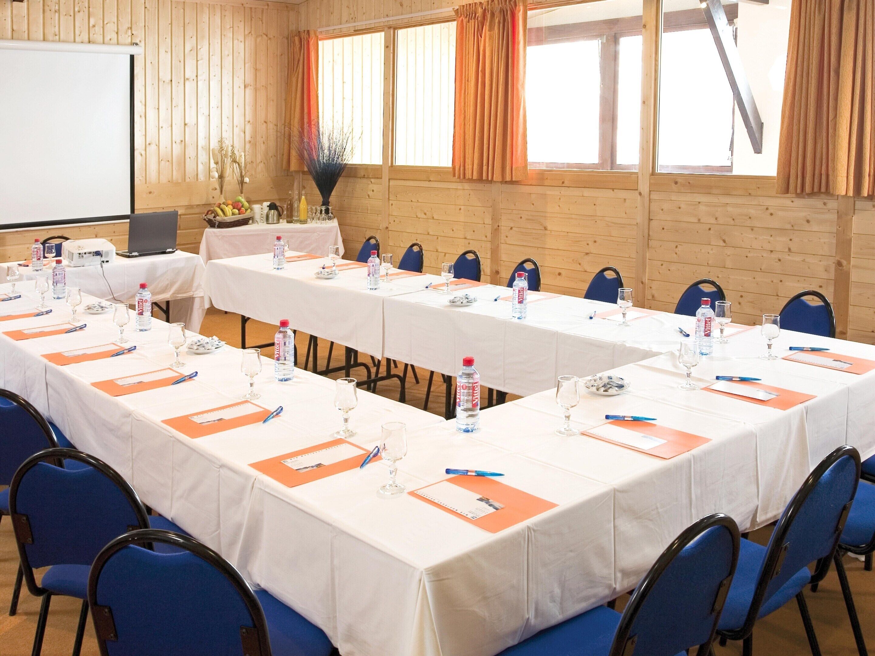A conference room with long tables, chairs, and presentation equipment.